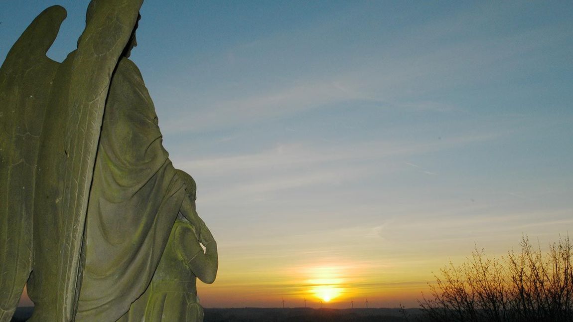 Statue eines Schutzengels beim Sonnenuntergang